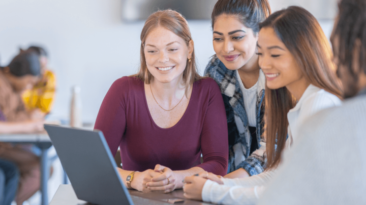 Drie vrouwen kijken samen naar het scherm van een laptop