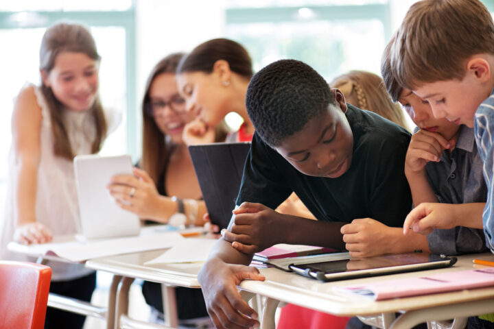 Kinderen rond tablet in de klas